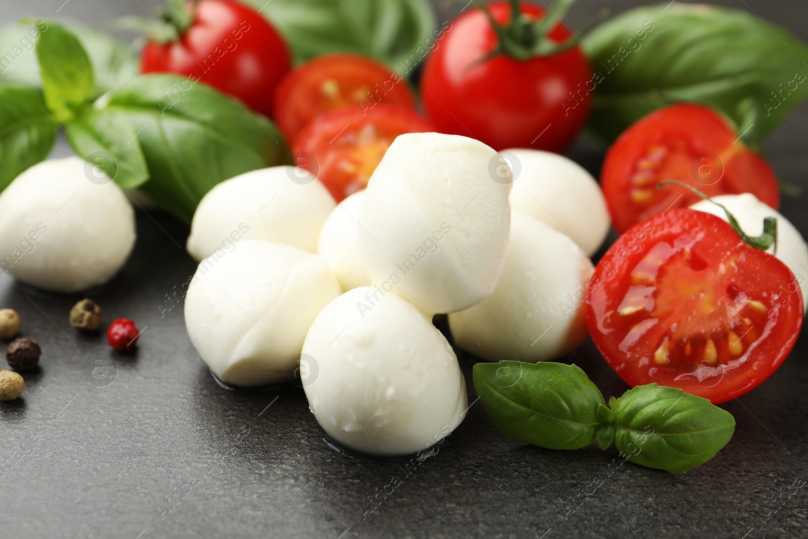 Mozzarella cheese, tomatoes, basil and peppercorns on grey table, closeup Photo of Mozzarella cheese, tomatoes, basil and peppercorns on grey table, closeup