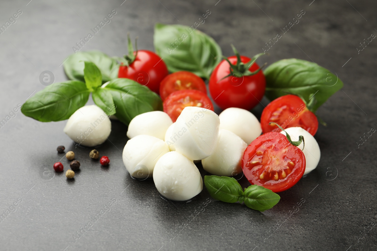 Mozzarella cheese, tomatoes, basil and peppercorns on grey table, closeup Photo of Mozzarella cheese, tomatoes, basil and peppercorns on grey table, closeup