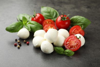 Photo of Mozzarella cheese, tomatoes, basil and peppercorns on grey table, closeup