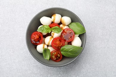 Photo of Tasty salad with mozzarella, tomatoes and basil on light table, top view