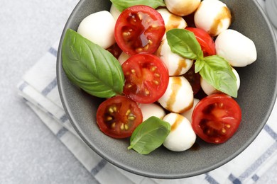 Photo of Tasty salad with mozzarella, tomatoes and basil on light table, top view