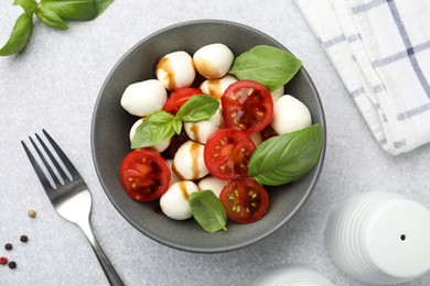Photo of Tasty salad with mozzarella, tomatoes and basil served on light table, flat lay