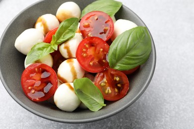 Photo of Tasty salad with mozzarella, tomatoes and basil on light table, closeup