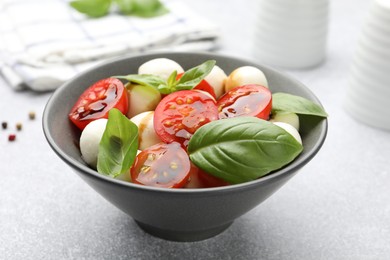 Photo of Tasty salad with mozzarella, tomatoes and basil on light table, closeup