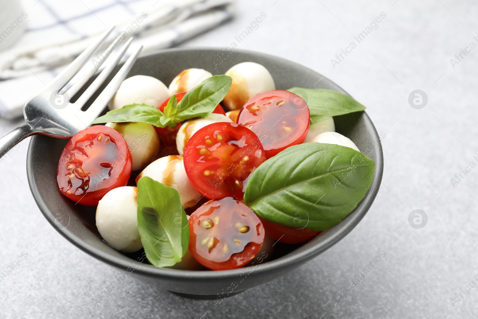 Tasty salad with mozzarella, tomatoes and basil served on light table, closeup Photo of Tasty salad with mozzarella, tomatoes and basil served on light table, closeup