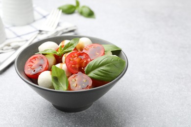 Photo of Tasty salad with mozzarella, tomatoes and basil on light table, closeup. Space for text