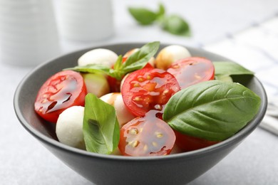 Photo of Tasty salad with mozzarella, tomatoes and basil on light table, closeup