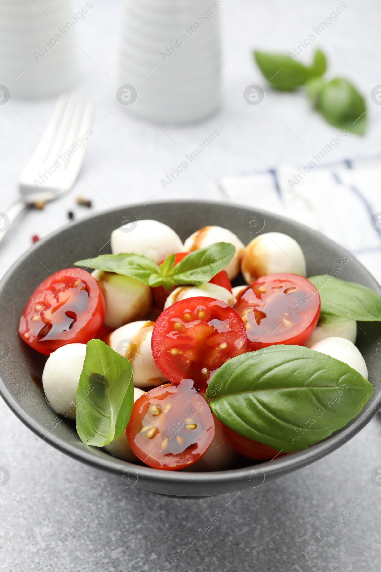 Tasty salad with mozzarella, tomatoes and basil on light table, closeup Photo of Tasty salad with mozzarella, tomatoes and basil on light table, closeup