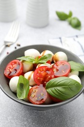 Photo of Tasty salad with mozzarella, tomatoes and basil on light table, closeup