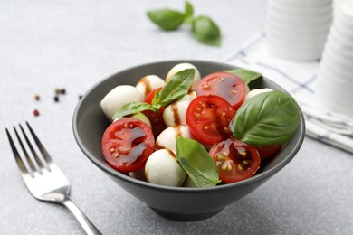 Photo of Tasty salad with mozzarella, tomatoes and basil served on light table, closeup