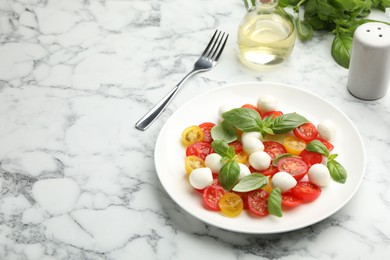 Photo of Tasty salad with mozzarella, tomatoes and basil served on white marble table. Space for text