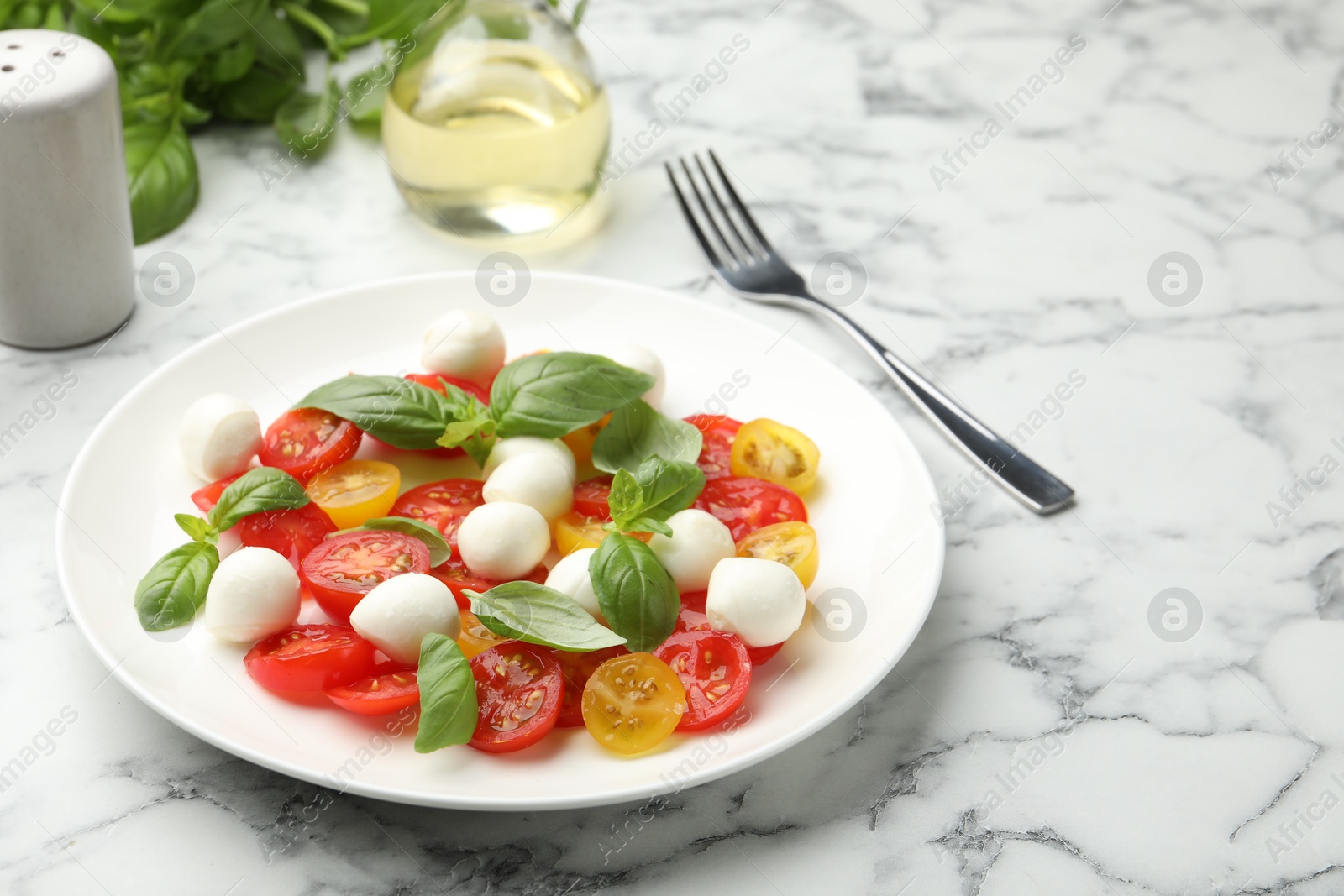 Tasty salad with mozzarella, tomatoes and basil served on white marble table Photo of Tasty salad with mozzarella, tomatoes and basil served on white marble table