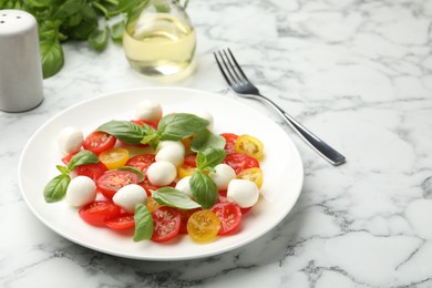 Photo of Tasty salad with mozzarella, tomatoes and basil served on white marble table