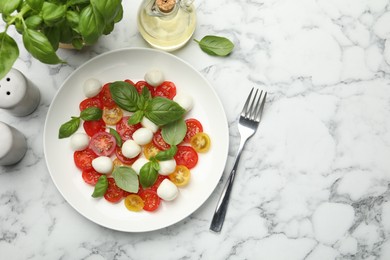Photo of Tasty salad with mozzarella, tomatoes and basil served on white marble table, flat lay