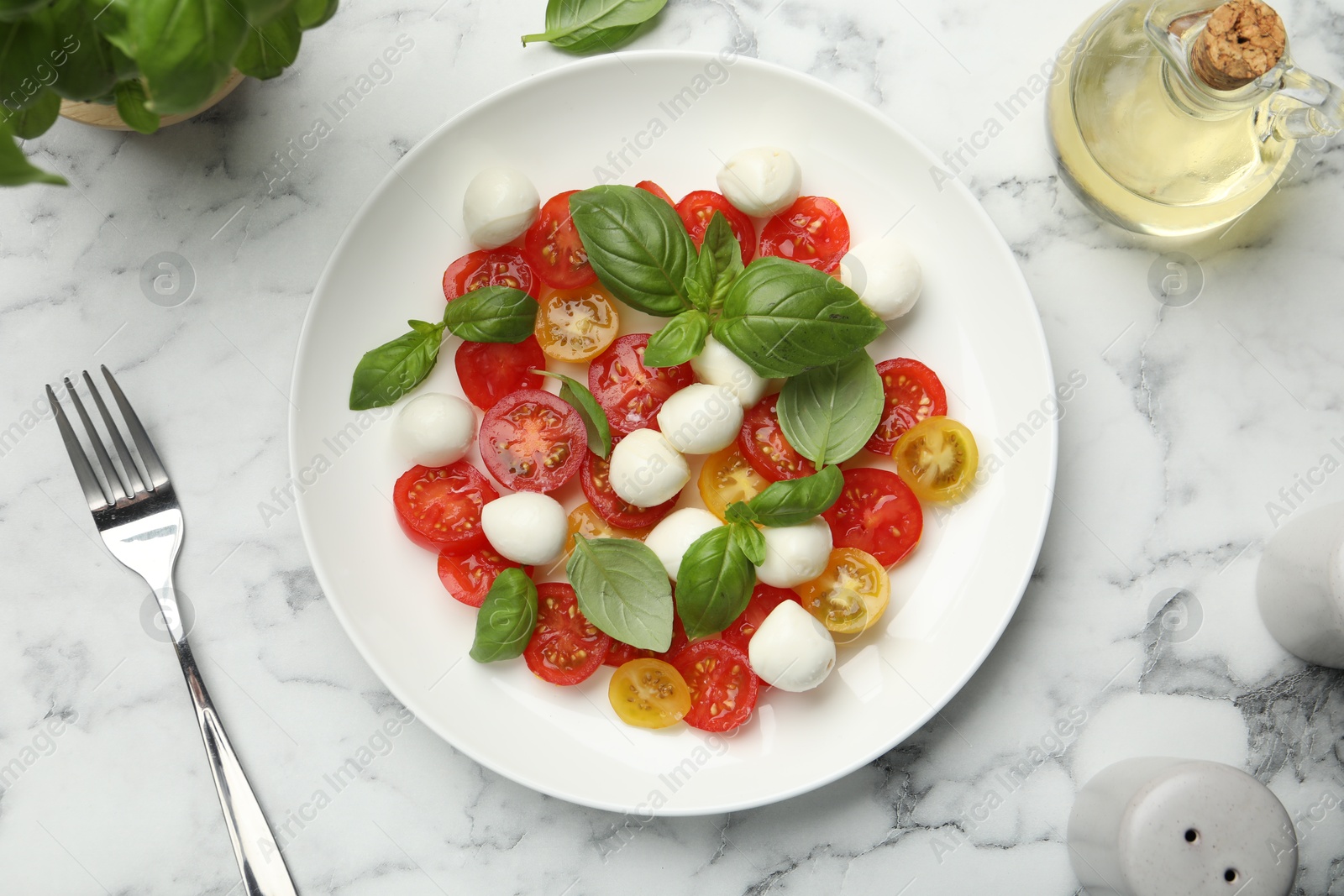 Tasty salad with mozzarella, tomatoes and basil served on white marble table, flat lay Photo of Tasty salad with mozzarella, tomatoes and basil served on white marble table, flat lay