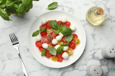 Photo of Tasty salad with mozzarella, tomatoes and basil served on white marble table, flat lay