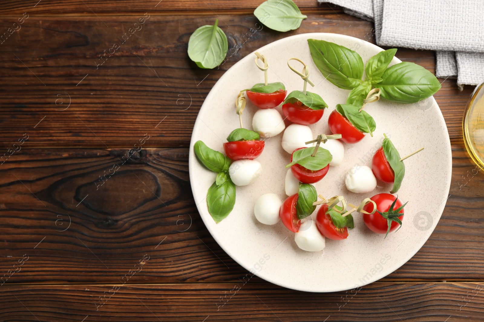 Appetizers with mozzarella, tomatoes and basil on wooden table, flat lay. Space for text Photo of Appetizers with mozzarella, tomatoes and basil on wooden table, flat lay. Space for text