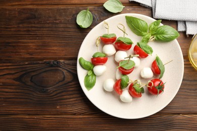 Photo of Appetizers with mozzarella, tomatoes and basil on wooden table, flat lay. Space for text