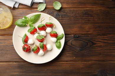 Photo of Appetizers with mozzarella, tomatoes and basil on wooden table, flat lay. Space for text
