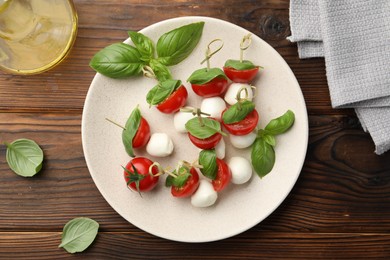 Photo of Appetizers with mozzarella, tomatoes and basil on wooden table, flat lay