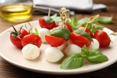 Photo of Appetizers with mozzarella, tomatoes and basil on wooden table, closeup