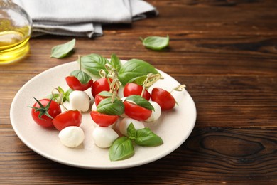 Photo of Appetizers with mozzarella, tomatoes and basil on wooden table