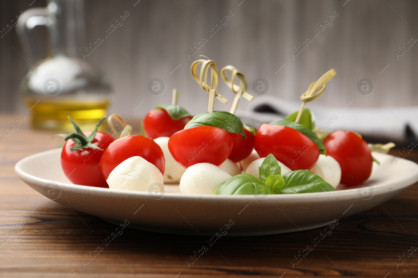 Appetizers with mozzarella, tomatoes and basil on wooden table, closeup Photo of Appetizers with mozzarella, tomatoes and basil on wooden table, closeup