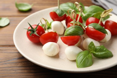 Photo of Appetizers with mozzarella, tomatoes and basil on wooden table, closeup