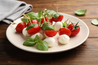 Photo of Appetizers with mozzarella, tomatoes and basil on wooden table, closeup