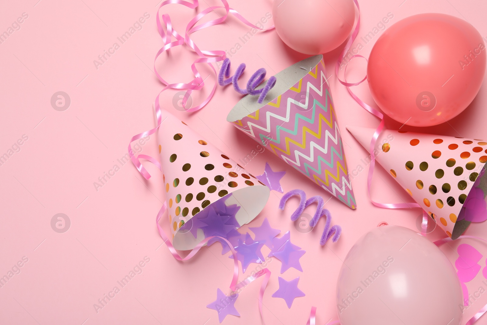 Party hats and festive decor on pink background, flat lay Photo of Party hats and festive decor on pink background, flat lay