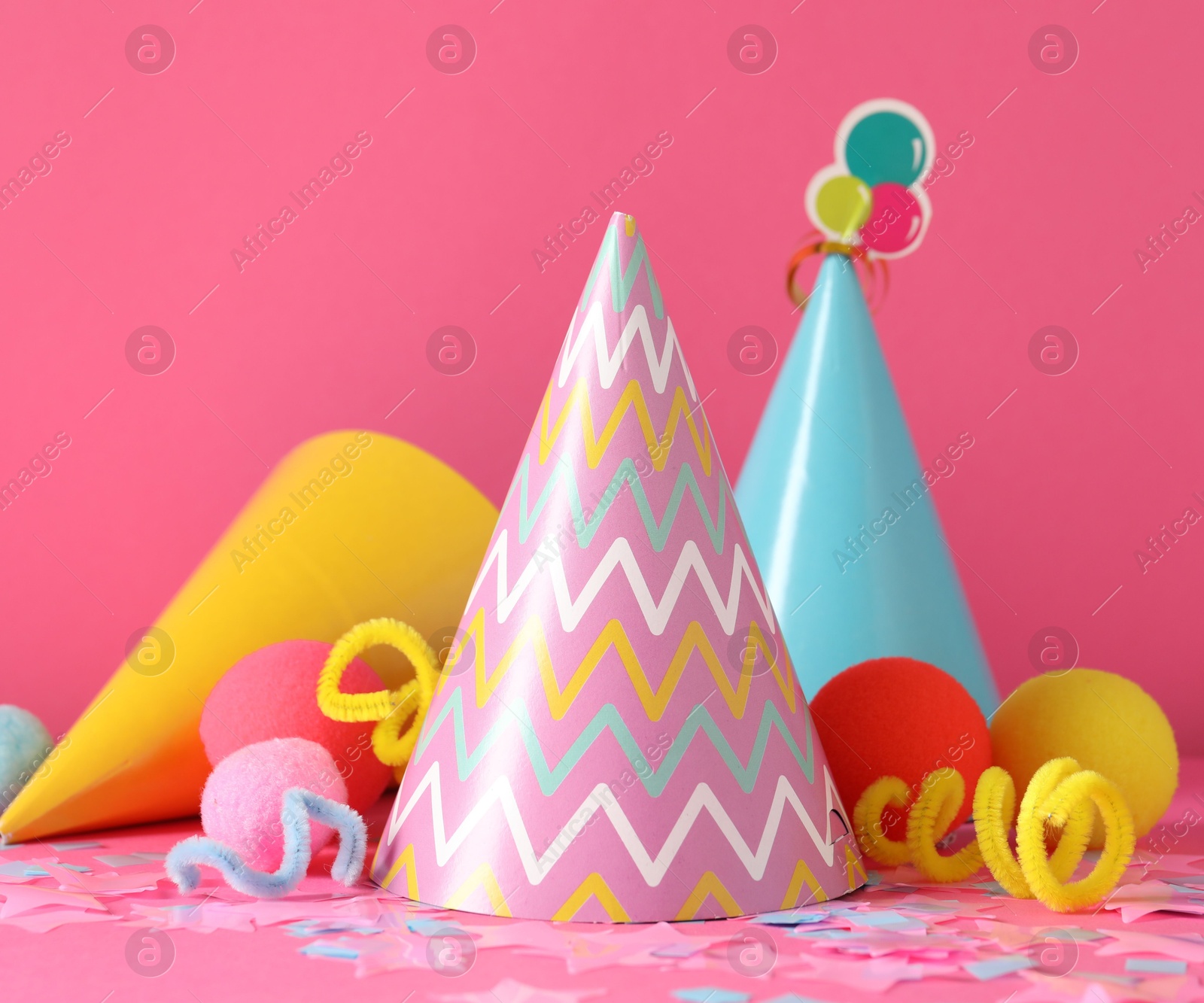 Party hats and festive decor on pink background Photo of Party hats and festive decor on pink background