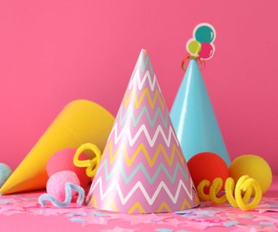 Photo of Party hats and festive decor on pink background