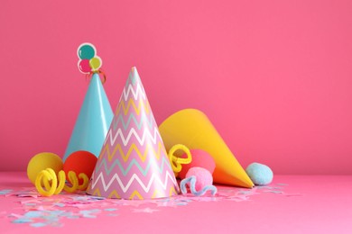 Photo of Party hats and festive decor on pink background. Space for text