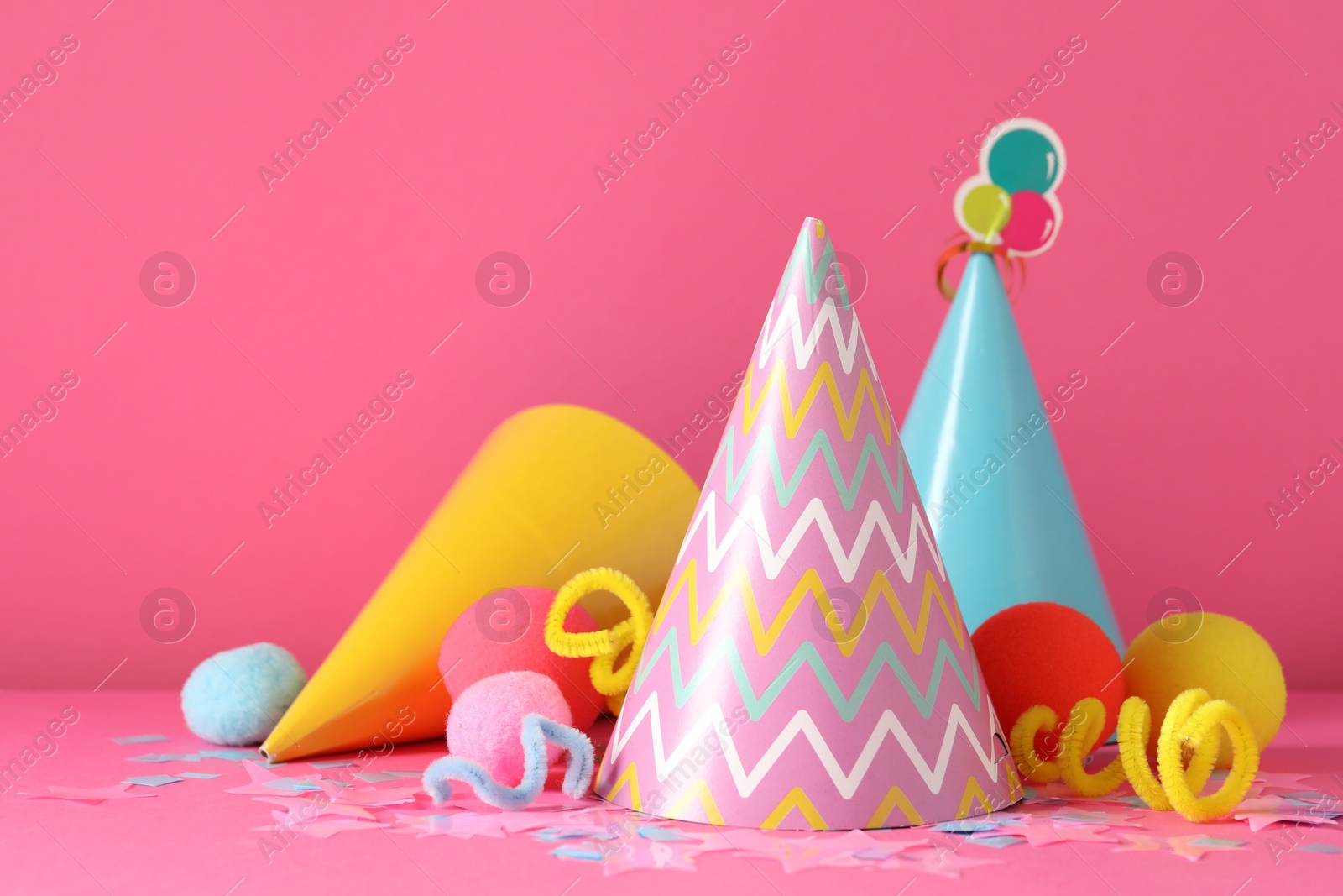Party hats and festive decor on pink background. Space for text Photo of Party hats and festive decor on pink background. Space for text