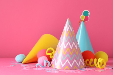 Photo of Party hats and festive decor on pink background. Space for text