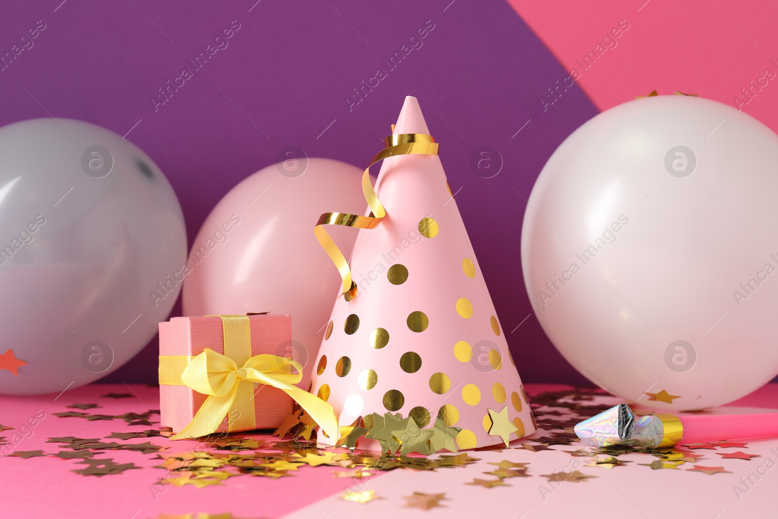 Party hat and festive decor on color background Photo of Party hat and festive decor on color background