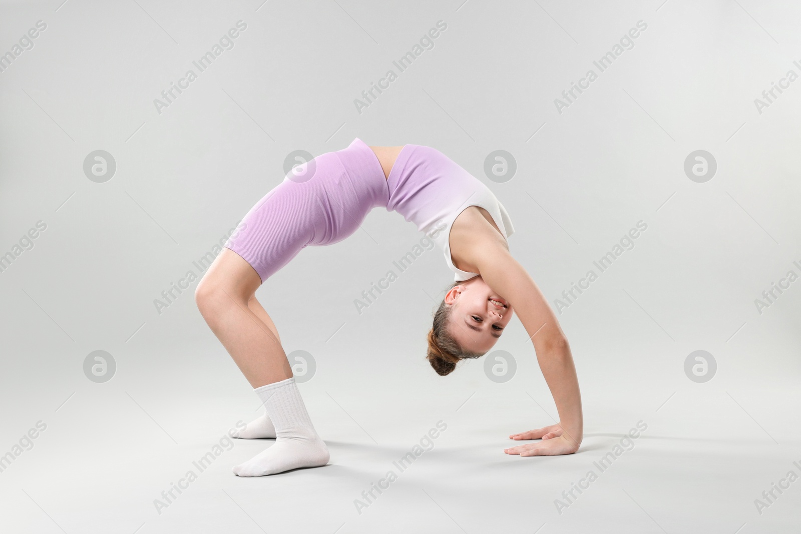 Girl in stylish clothes dancing on light grey background Photo of Girl in stylish clothes dancing on light grey background