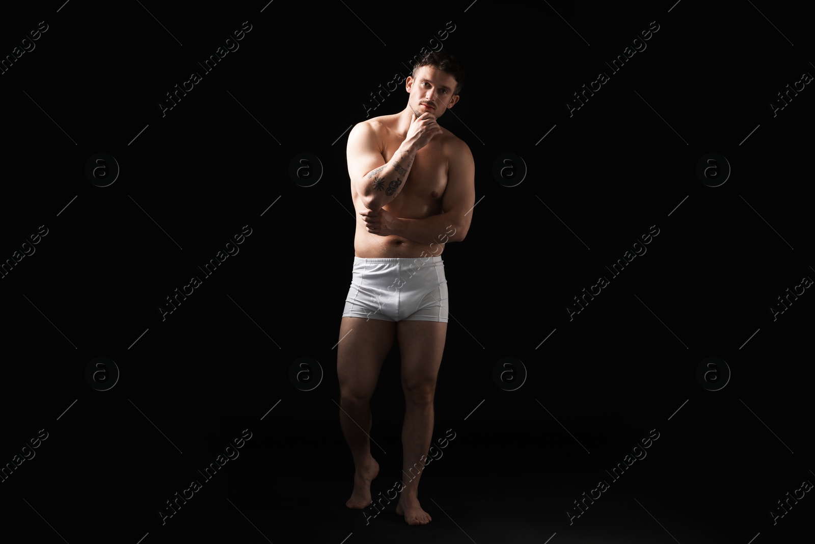 Young man in stylish white underwear on black background Photo of Young man in stylish white underwear on black background