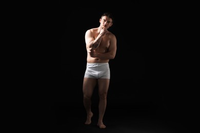 Photo of Young man in stylish white underwear on black background