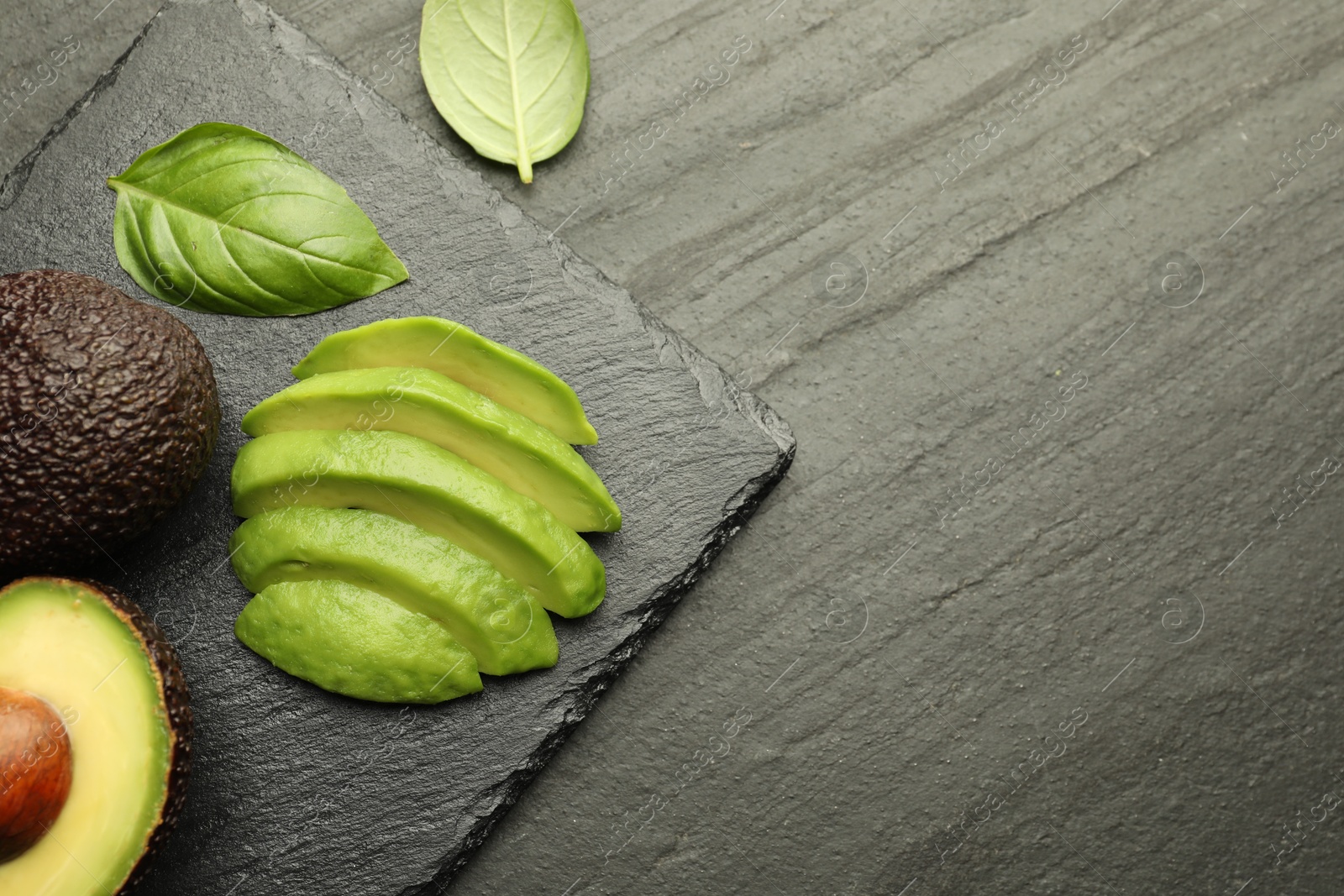 Tasty ripe green avocados and basil on black table, flat lay. Space for text Photo of Tasty ripe green avocados and basil on black table, flat lay. Space for text