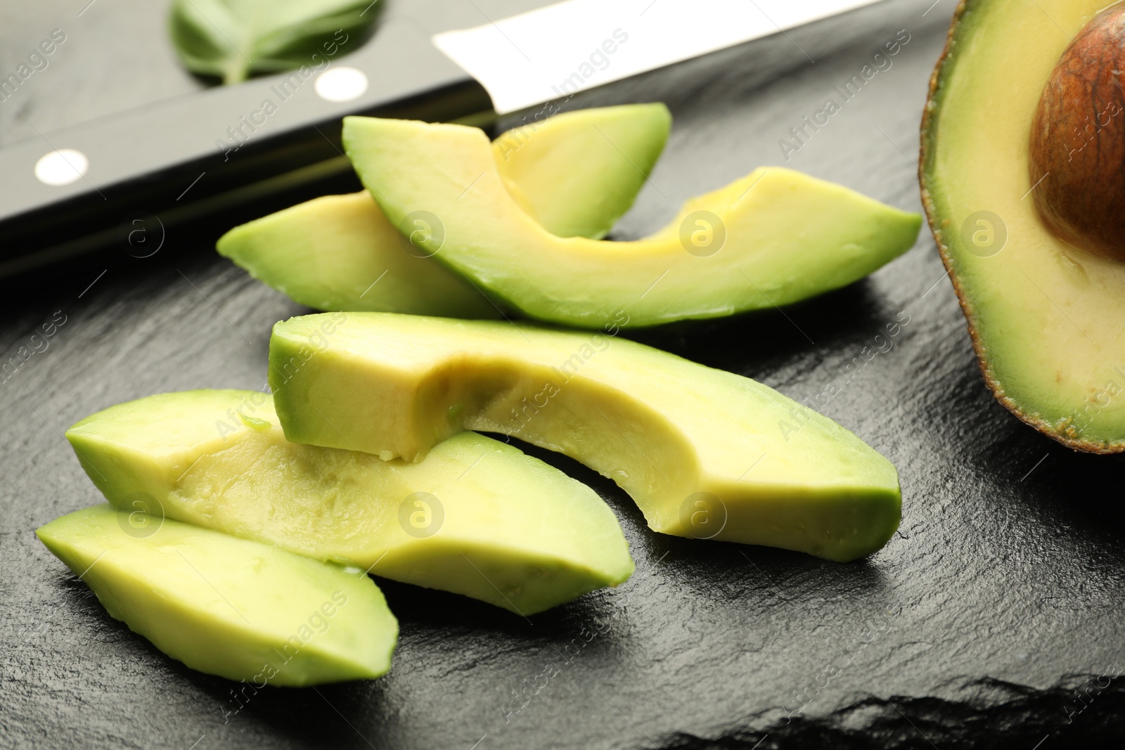 Tasty ripe green avocado and knife on table, closeup Photo of Tasty ripe green avocado and knife on table, closeup