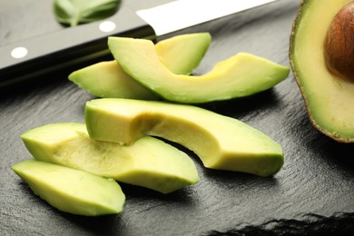 Photo of Tasty ripe green avocado and knife on table, closeup