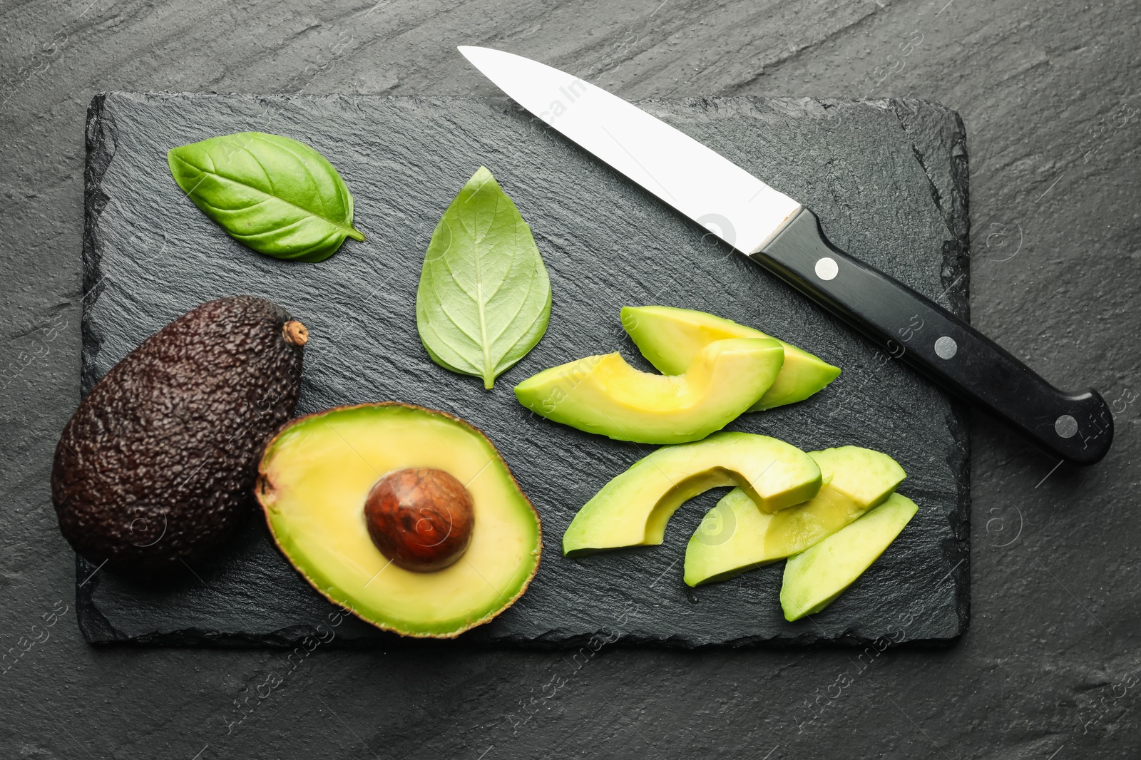 Tasty ripe green avocados, basil and knife on black table, flat lay Photo of Tasty ripe green avocados, basil and knife on black table, flat lay