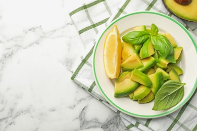 Photo of Tasty ripe green avocado, basil and lemon on white marble table, top view. Space for text