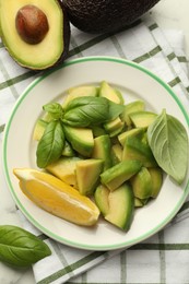 Photo of Tasty ripe green avocados, basil and lemon on table, flat lay