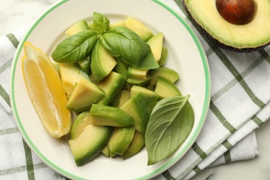 Photo of Tasty ripe green avocados, basil and lemon on table, flat lay