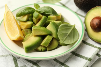 Photo of Tasty ripe green avocados, basil and lemon on table, closeup