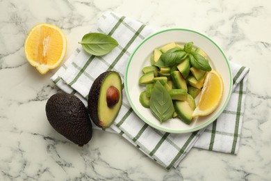 Photo of Tasty ripe green avocados, basil and lemon on white marble table, flat lay