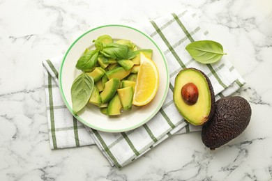 Photo of Tasty ripe green avocados, basil and lemon on white marble table, flat lay