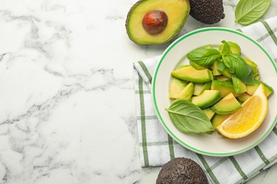 Photo of Tasty ripe green avocados, basil and lemon on white marble table, flat lay. Space for text